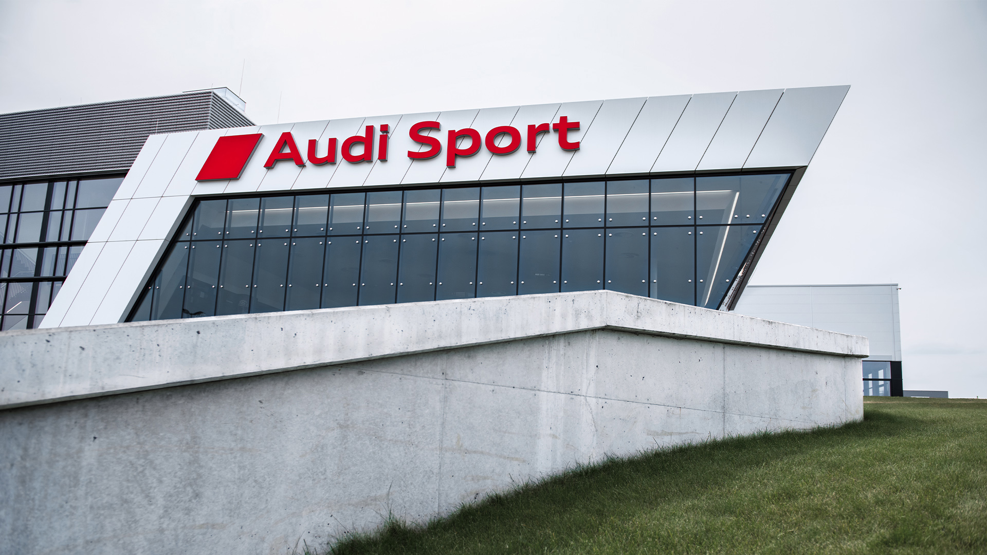 Das Audi Sport Gebäude hinter einer schmalen Wand