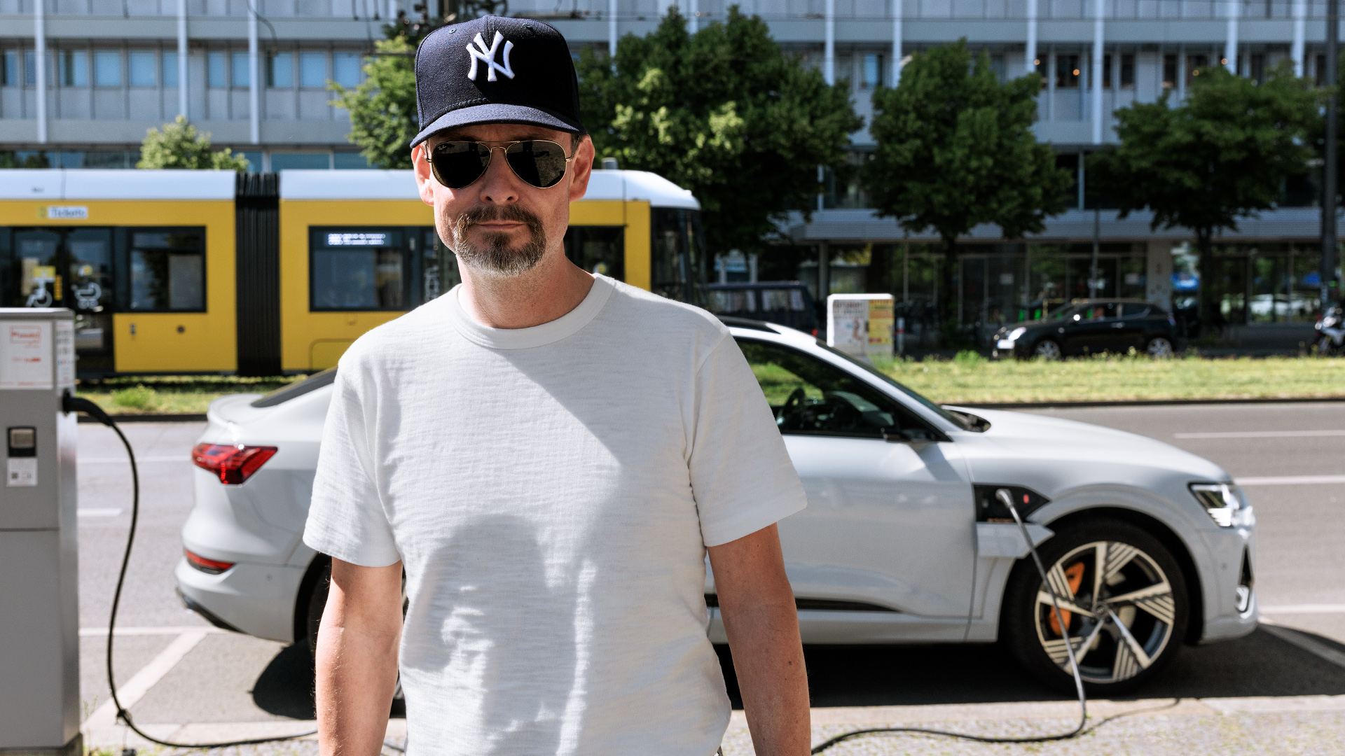 Marco Voigt schließt seinen weißen Audi e-tron Sportback in der Berliner City an eine Ladesäule an.